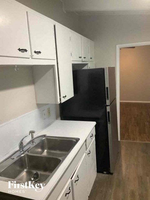 A kitchen with white cabinets and a black refrigerator.