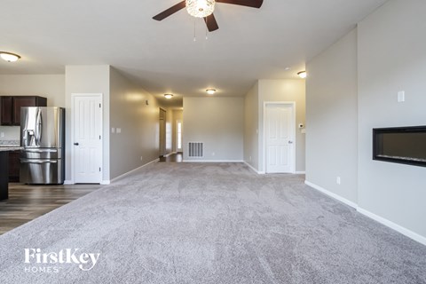 a living room with a carpet and a ceiling fan