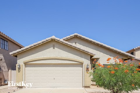 A house with a garage door and a tree with orange flowers in front.