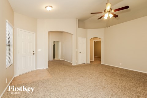 A spacious room with a ceiling fan and carpeted floor.