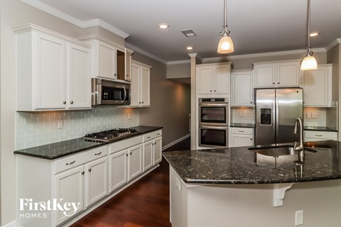 a white kitchen with granite counter tops and stainless steel appliances