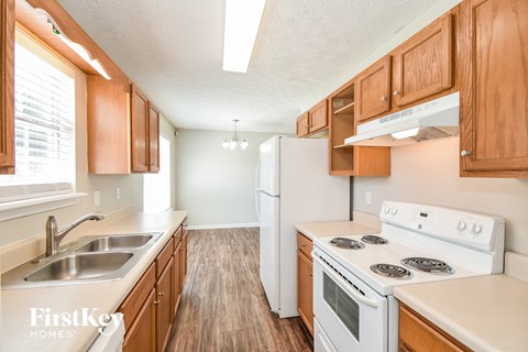 a kitchen with wood flooring and white appliances and wooden cabinets