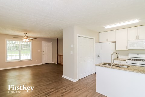a kitchen and living room with white cabinets and a counter top