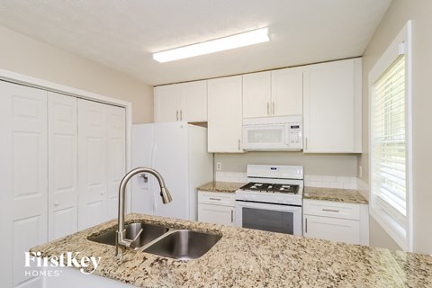 a kitchen with white cabinets and granite counter tops and a sink