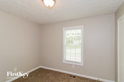a bedroom with a window and a carpeted floor