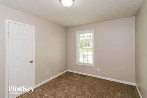 an empty bedroom with a white door and a window