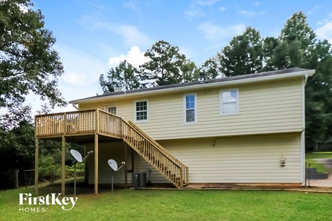a yellow house with a deck on top of a wood deck