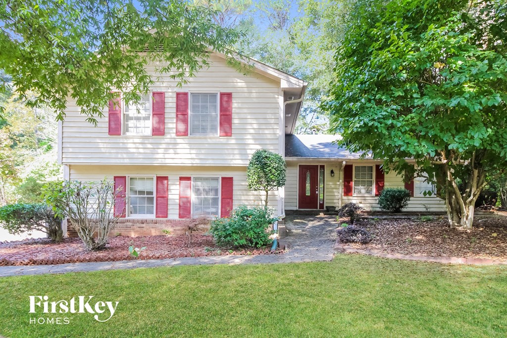 a white house with red shutters and a lawn and trees