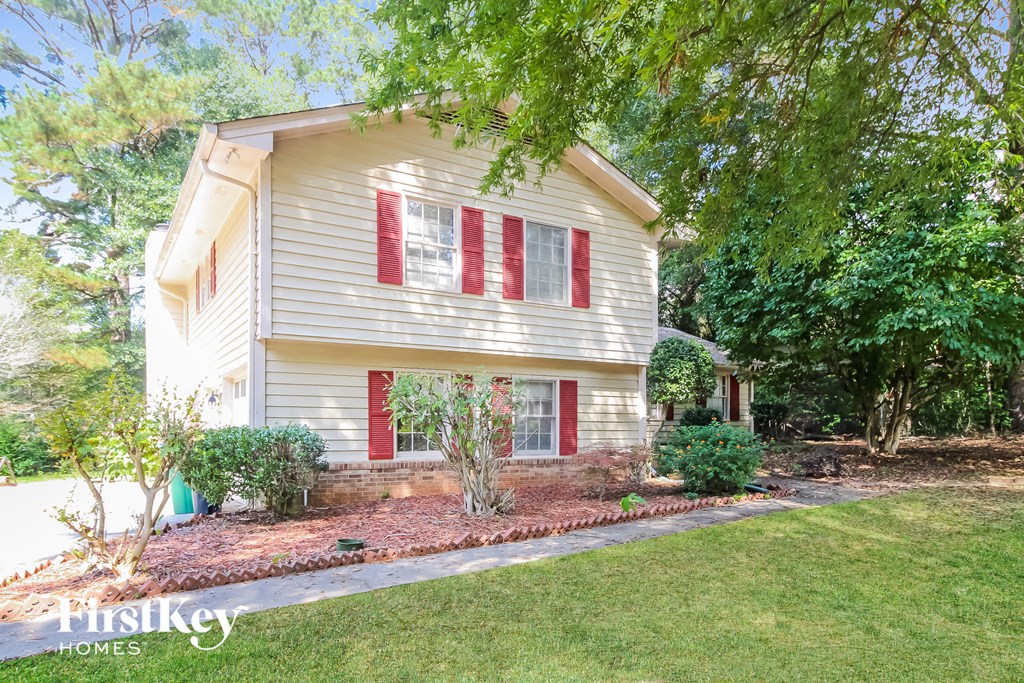 a small white house with red window shutters and a lawn