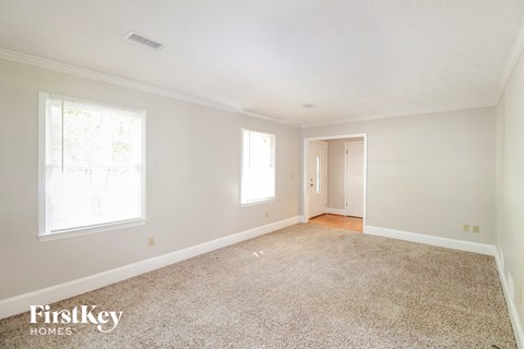 a spacious living room with carpet and white walls