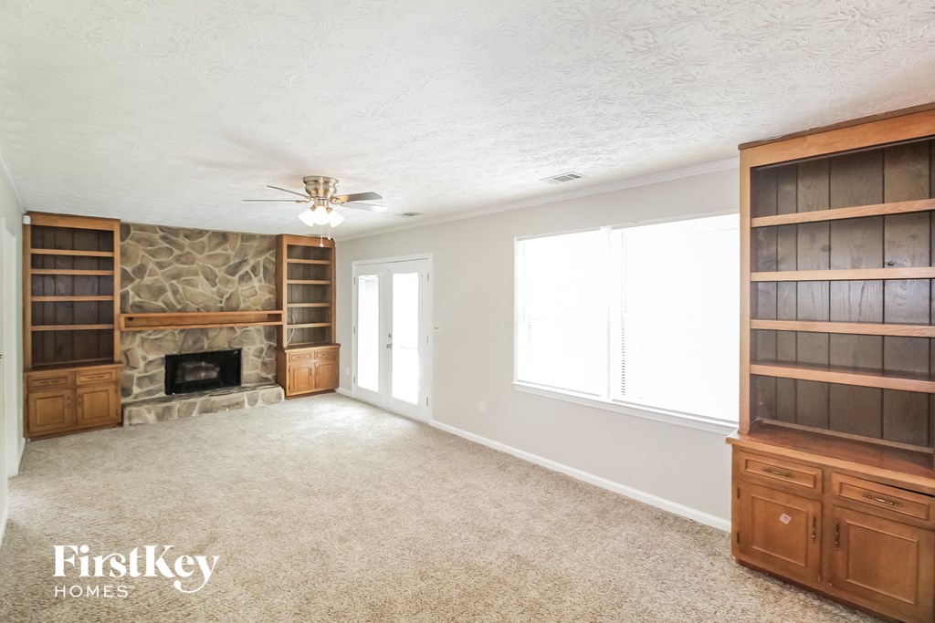 a living room with a stone fireplace and wooden shelves