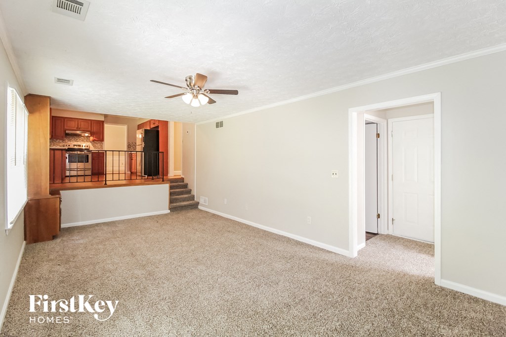 a living room with carpet and a ceiling fan