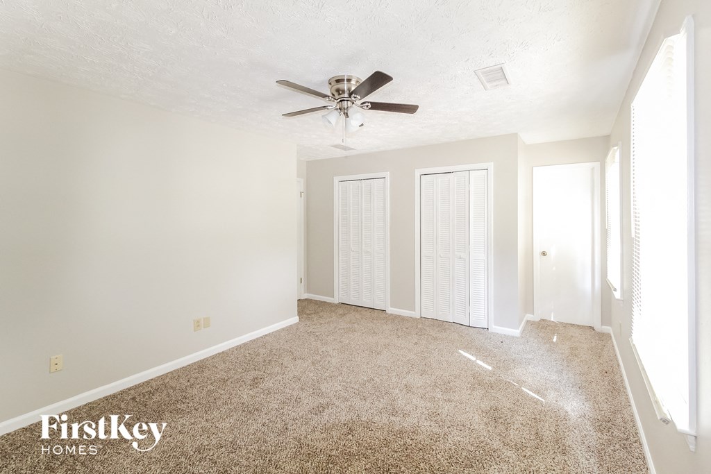 a spacious living room with carpet and a ceiling fan