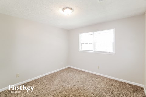 a bedroom with white walls and carpet and a window