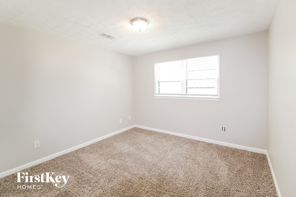 a spacious room with carpet and a window