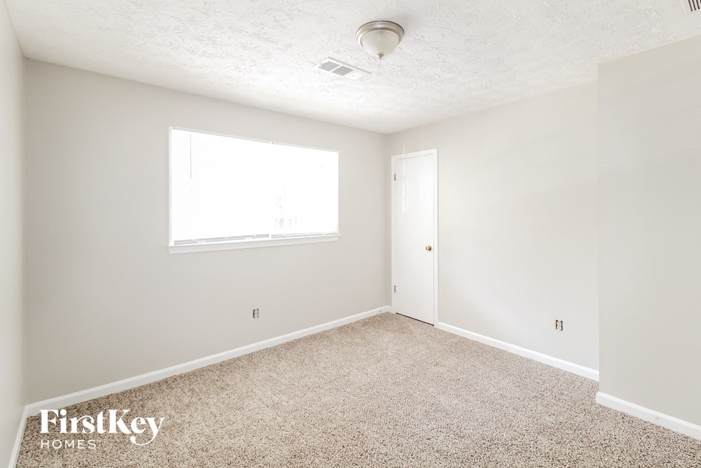 a bedroom with white walls and carpet and a window