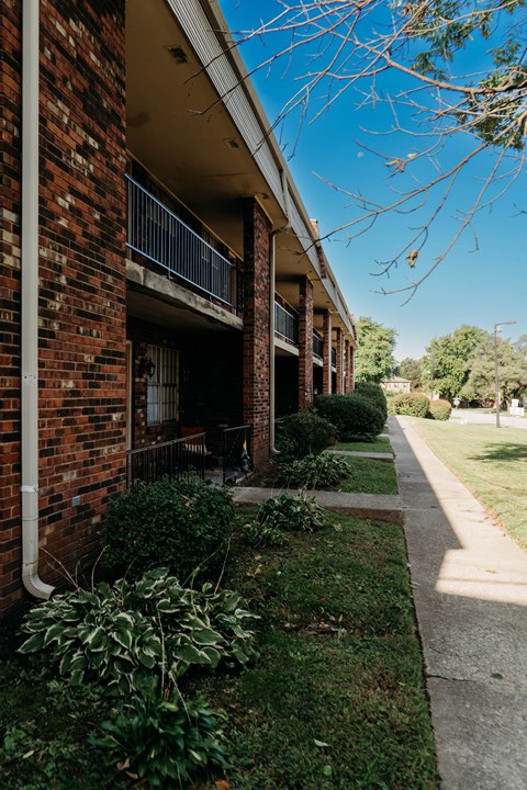 a brick apartment building with a sidewalk in front of it