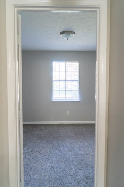 an empty room with a window and a carpet