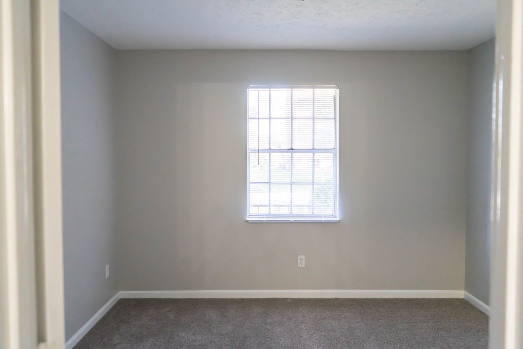 a bedroom with a window and a carpeted floor