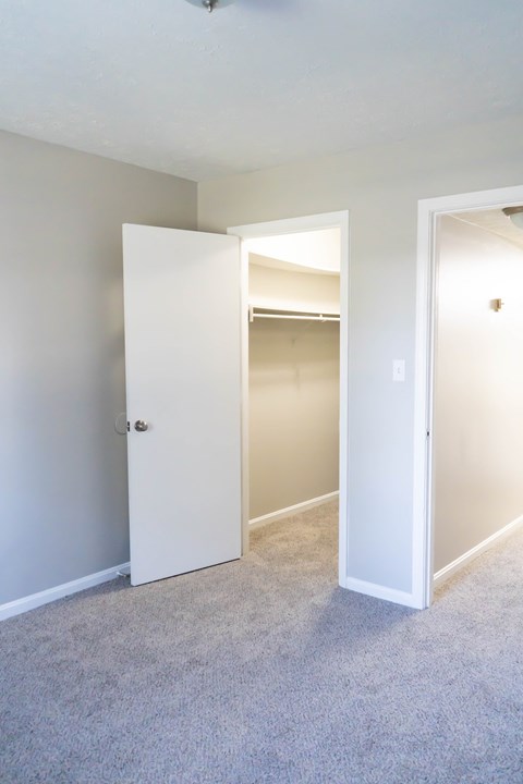 an empty bedroom with a closet and an open door