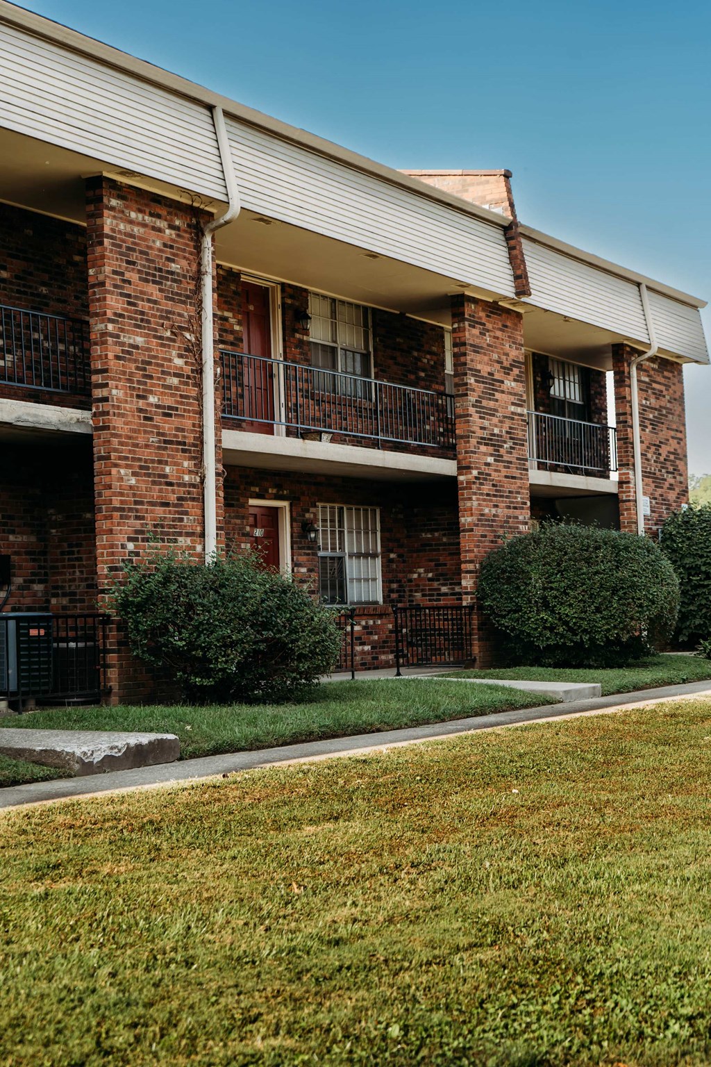 an apartment building with red brick and green grass