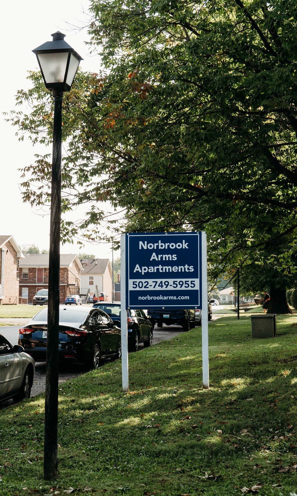 a sign in the grass next to a parking lot