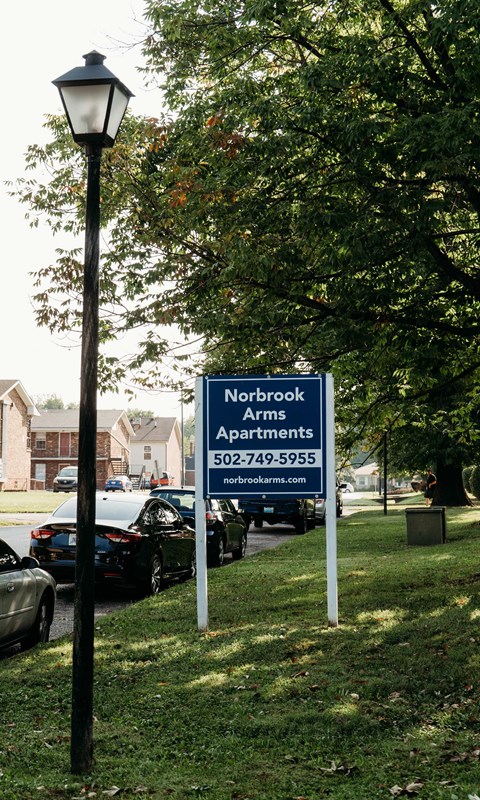 a sign in the grass next to a parking lot