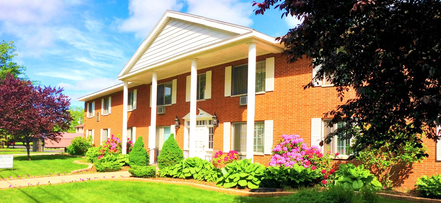 A red brick house with white columns and a white door.