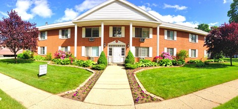 A red brick building with a white roof and a sign in front.