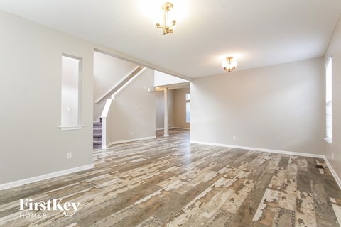 the living room and dining room with wood flooring and white walls