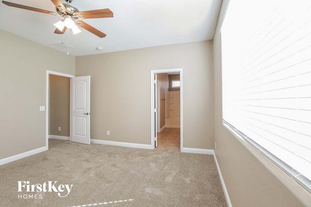 a bedroom with a large window and a ceiling fan