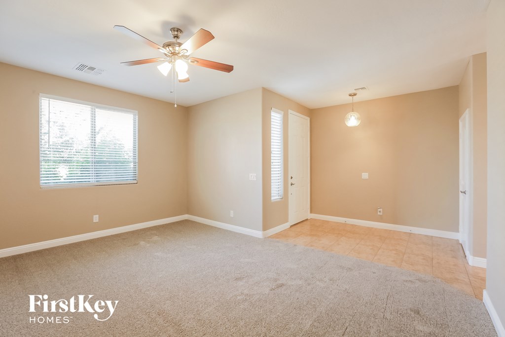 an empty living room with a ceiling fan and a window