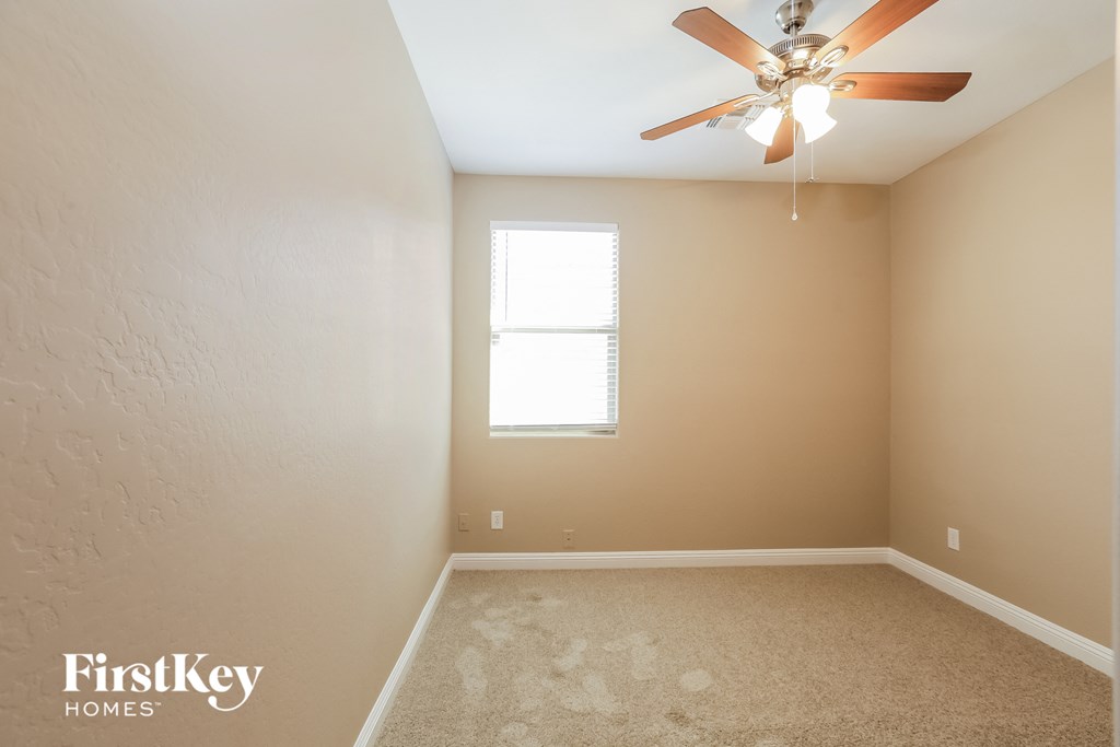 a empty room with a ceiling fan and a window