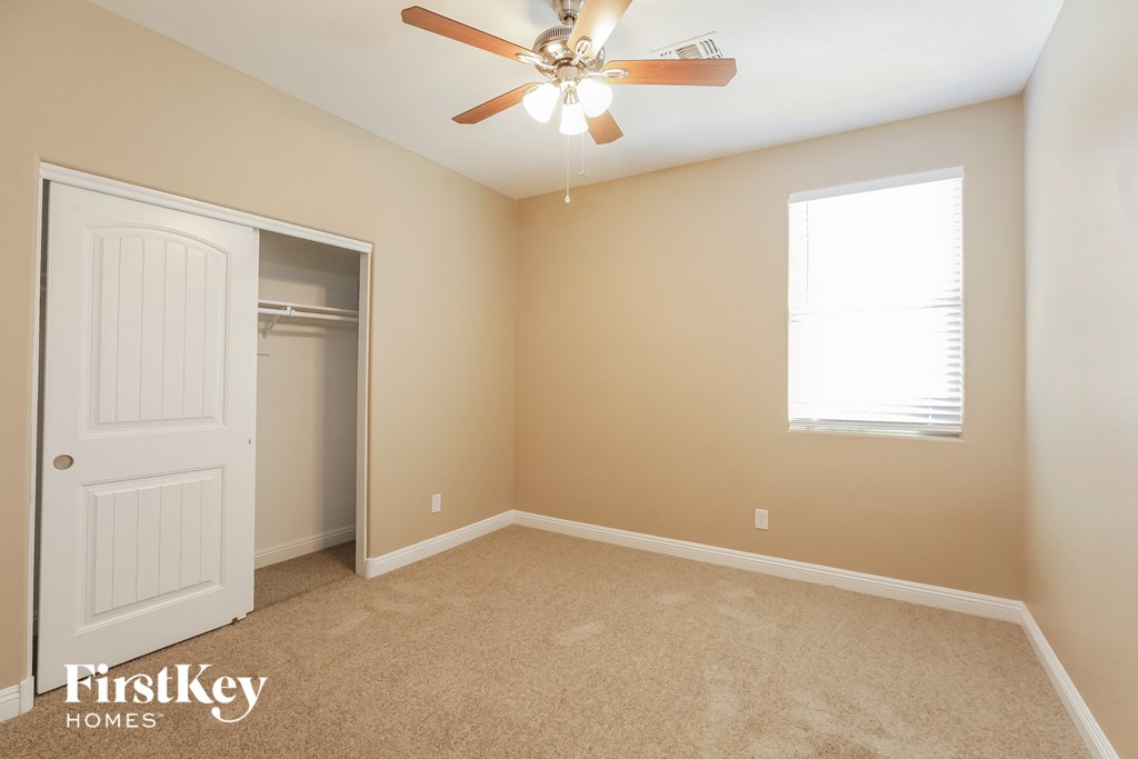 a bedroom with a ceiling fan and a closet