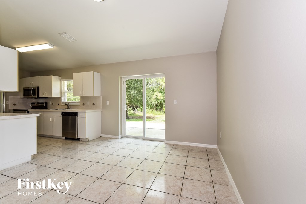 A spacious kitchen and living room with white cabinets and a tiled floor.