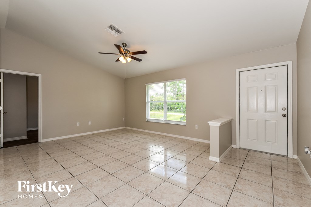 A spacious room with a ceiling fan and a door leading to a balcony.