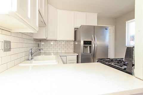 a kitchen with white counters and a stainless steel refrigerator