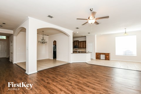A spacious living room with a ceiling fan and hardwood floors.