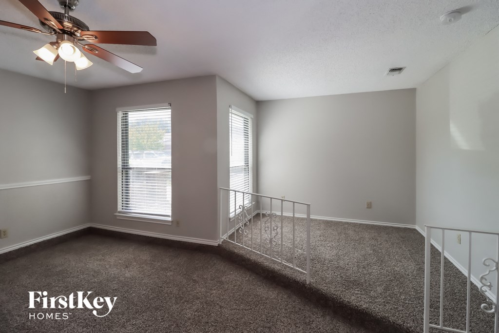 A room with a carpet floor and a ceiling fan.