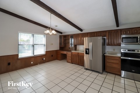 A kitchen with wooden cabinets and a tile floor.