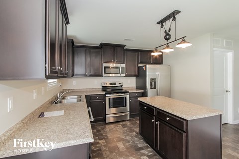 A kitchen with dark brown cabinets and a granite countertop.