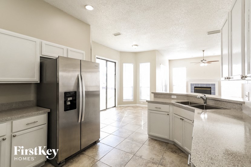 A kitchen with a stainless steel refrigerator and white cabinets.