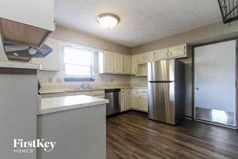 A kitchen with a refrigerator, sink, and cabinets.