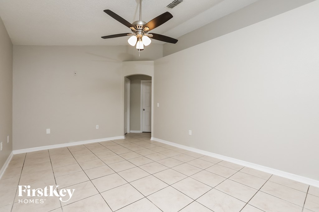 A spacious room with a ceiling fan and tiled floor.
