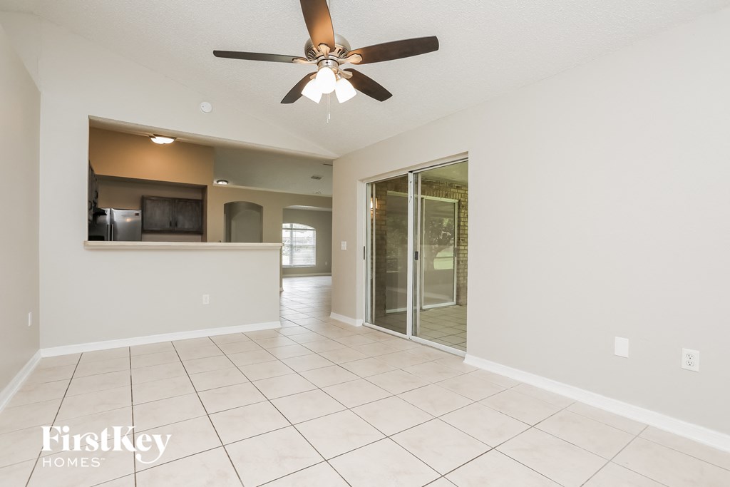 A spacious room with a ceiling fan and a kitchen area in the background.