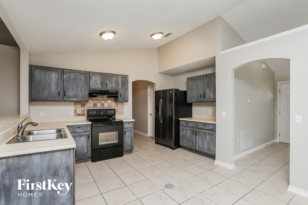 A kitchen with a sink, stove, and refrigerator.