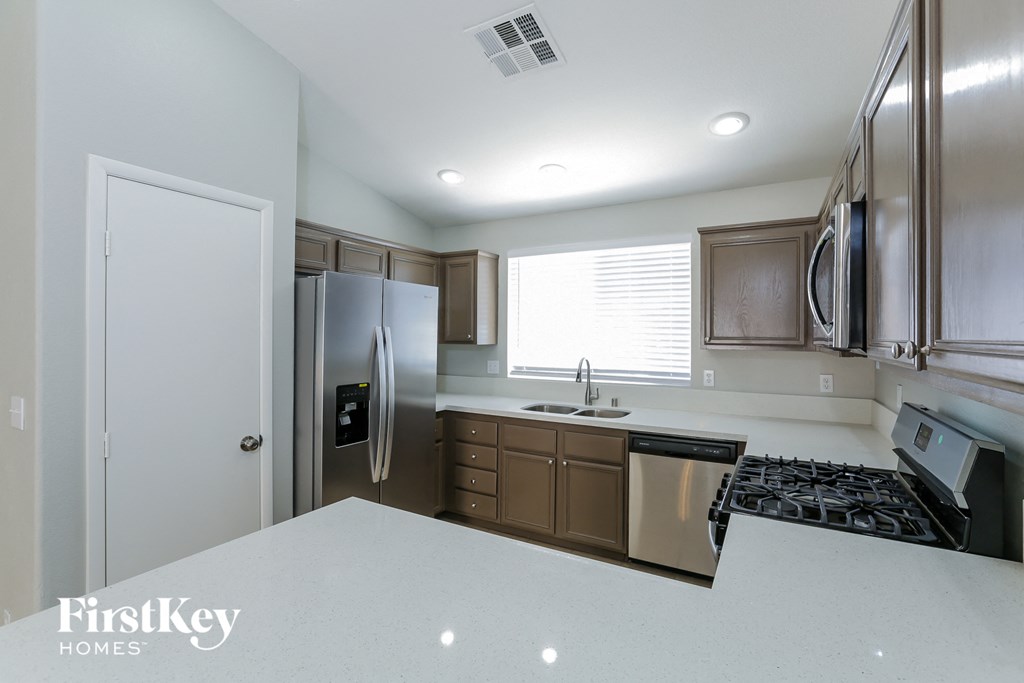 A kitchen with a white counter top and a stainless steel refrigerator.