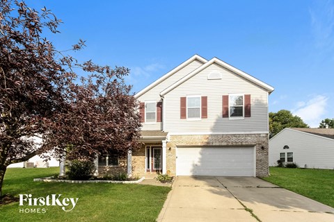 a white house with a white garage door and a tree