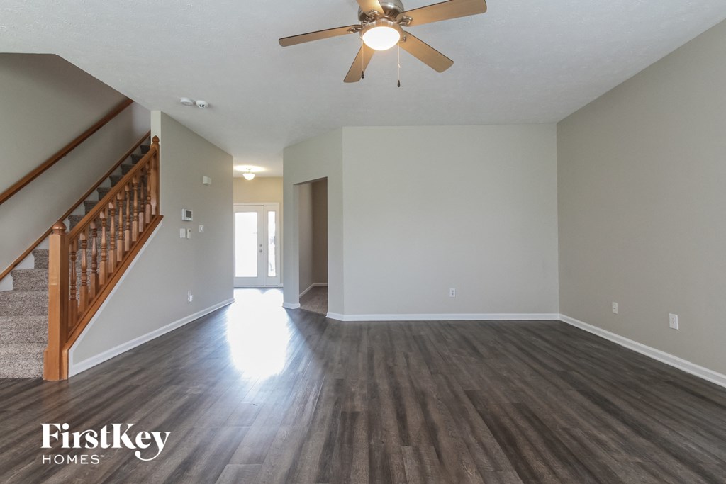 an empty living room with wood floors and a ceiling fan