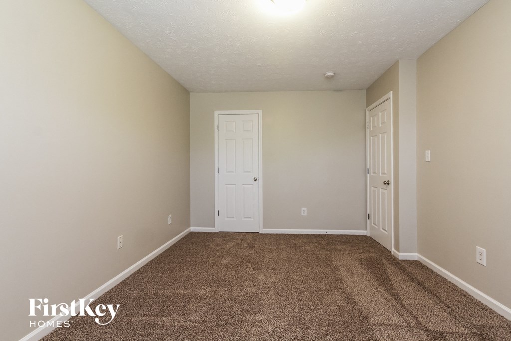 a carpeted living room with a white door and a white closet